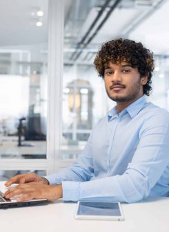Focused professional engaged in work on a laptop at a bright, contemporary office with an open space layout.