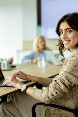 Confident businesswoman engages in a meeting, her smile reflecting success and teamwork in a modern office setting.